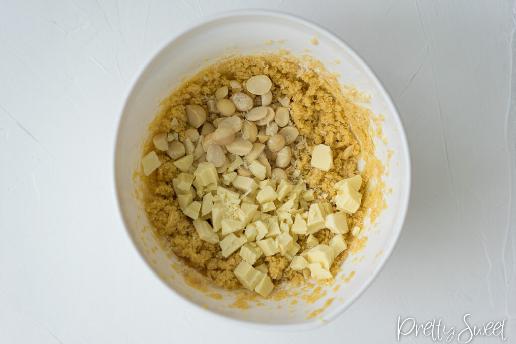 creamed cookie dough with added macadamia nuts and chopped white chocolate on top in a white bowl