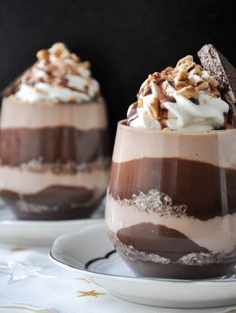 Chocolate hazelnut dessert in a glass with layers, ganache and whipped cream