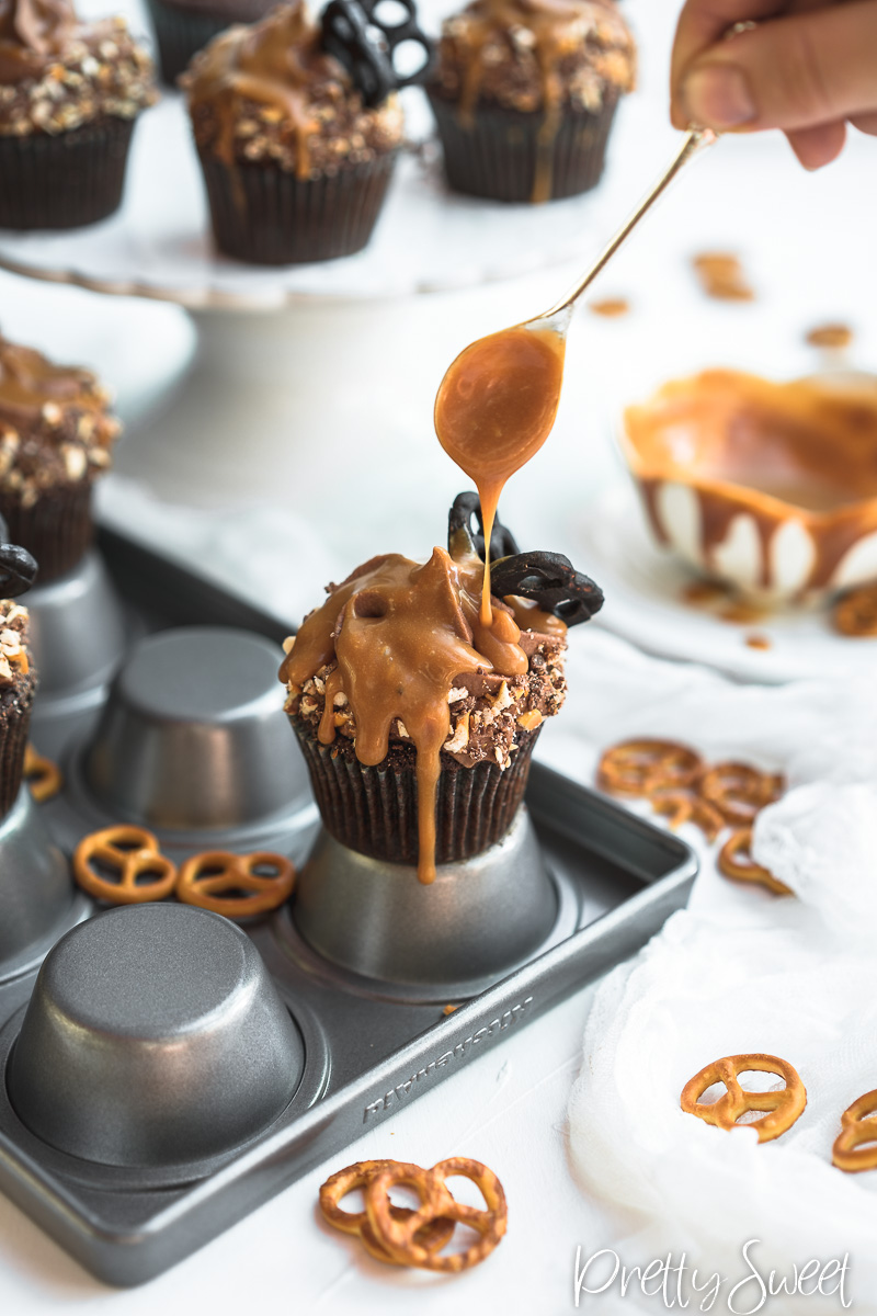 Salted Caramel filled Chocolate Cupcakes with whipped milk chocolate ganache and chocolate butterfly pretzels on a cupcake tin