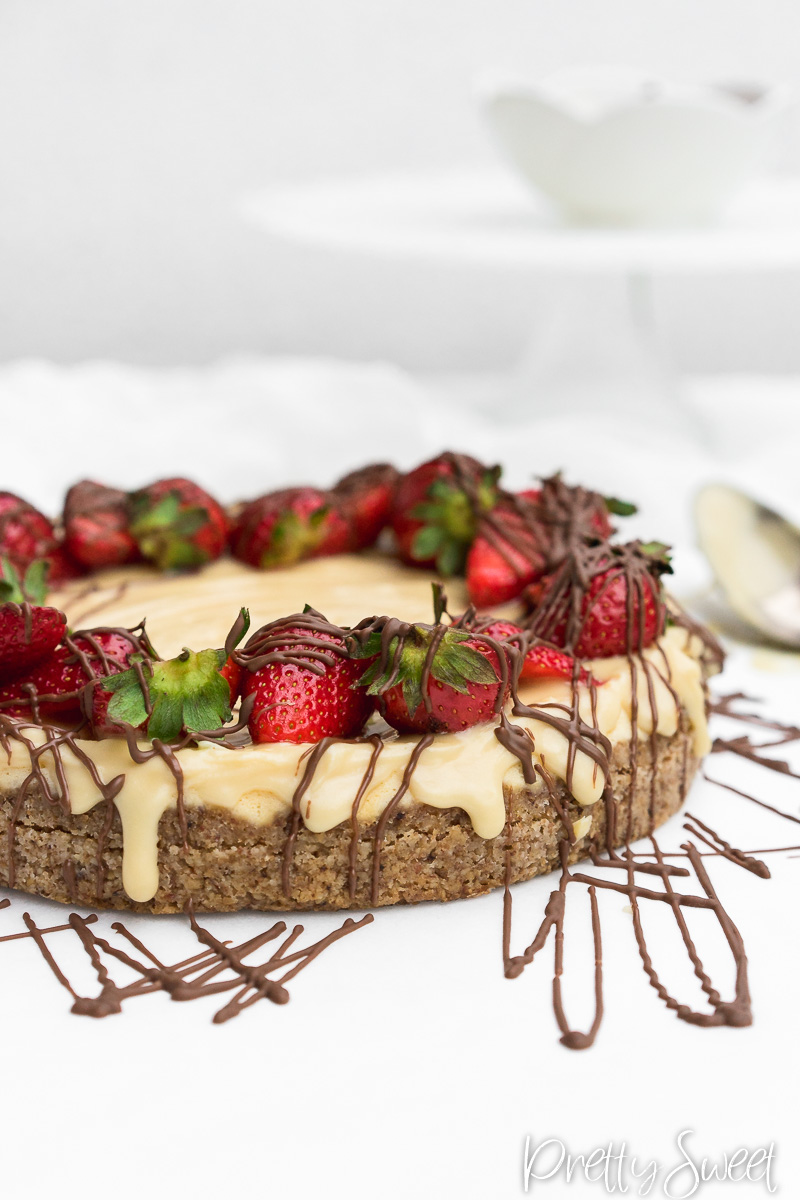 A cut piece of a protein cheesecake with straberries and drizzeled chocolate