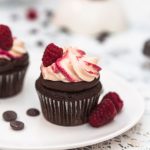 Raspberry chocolate cupcake with cream cheese frosting topped with raspberries up close