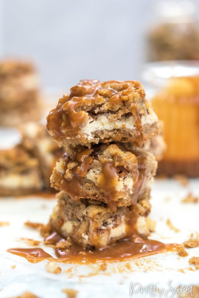Apple Crumble Cheesecake Bars with Salted Caramel Sauceon in a tower stack in 3,one with a bite
