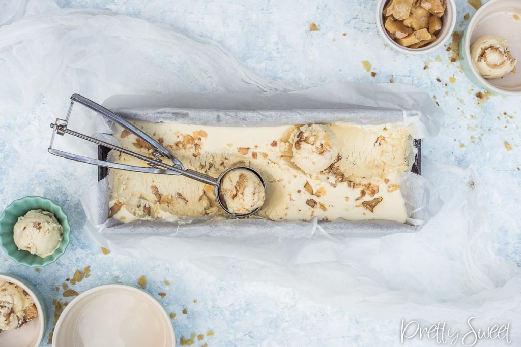 a scoop of macadamia brittle ice cream scooped with an ice cream scooper in a loaf tin
