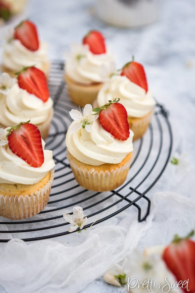 Strawberry filled cupcakes with a white chocolate whipped ganache swirl on a black round wire rack