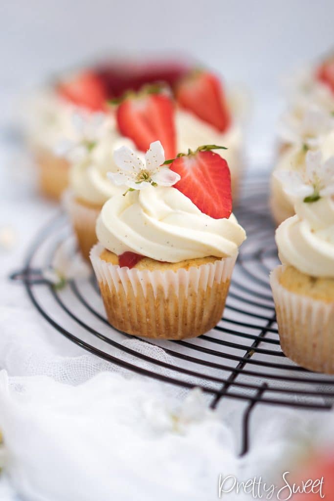 Close up of a strawberry and whtie chococlate cupcakes on a wire rack