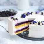 Blueberry mousse cake with greek yogurt and flower decoration with a piece being taken away