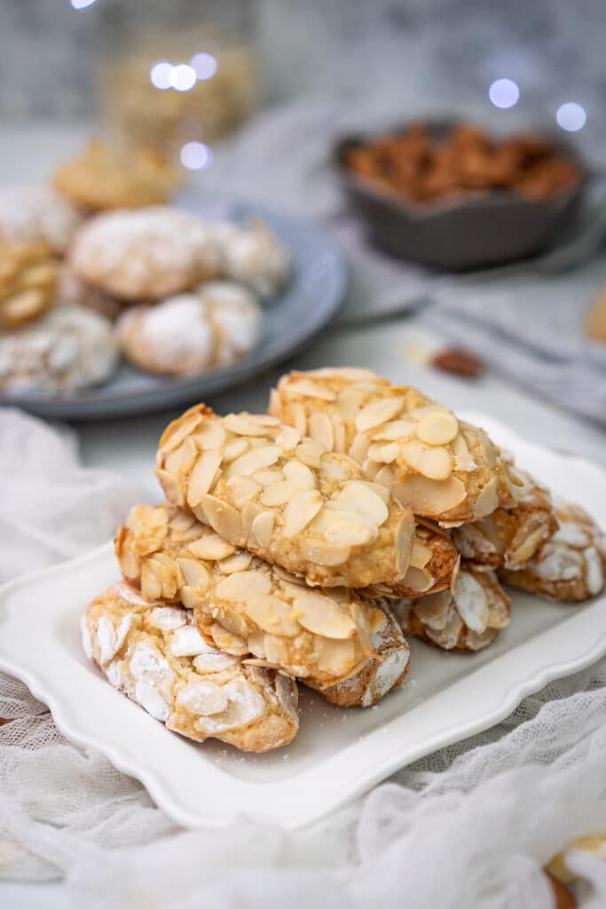 oval almond cookies with slivered almonds on the outside stacked on a plate