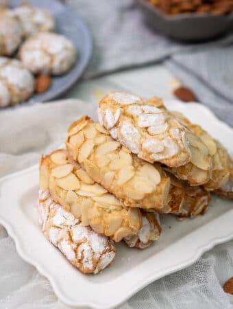 oval shewy almond cookies stacked in a pyramid on a rectangular plate