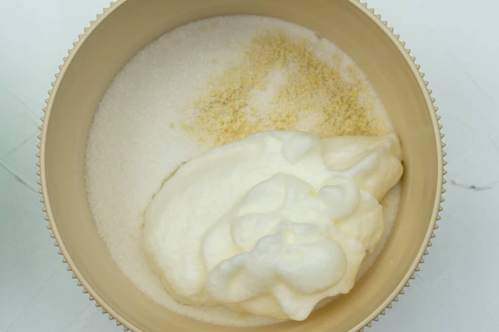 Almond flour and sugar with whipped egg whites in a bowl