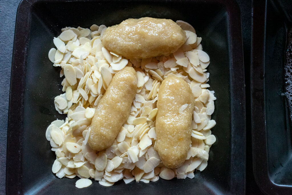 oval shaped amaretti cookie dough on slivered almonds in a plate