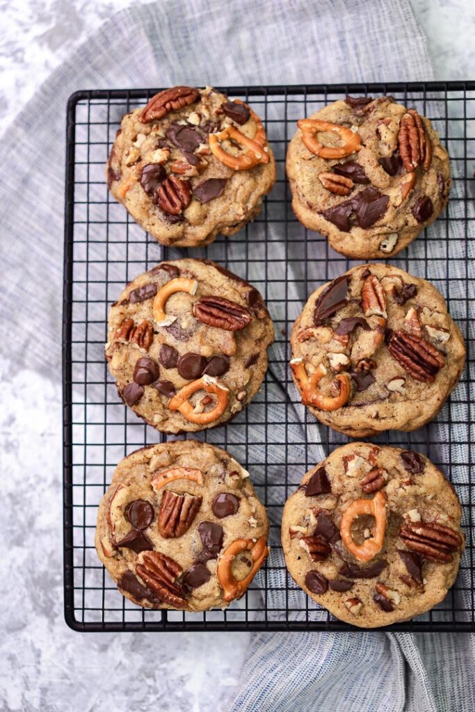 browned butter chewy pecan pretzel cookies lined on a rack