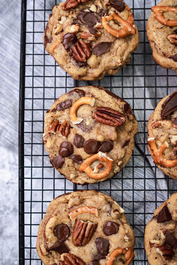 cookie on a rack with pretzel, pecan and chocolate chips on top