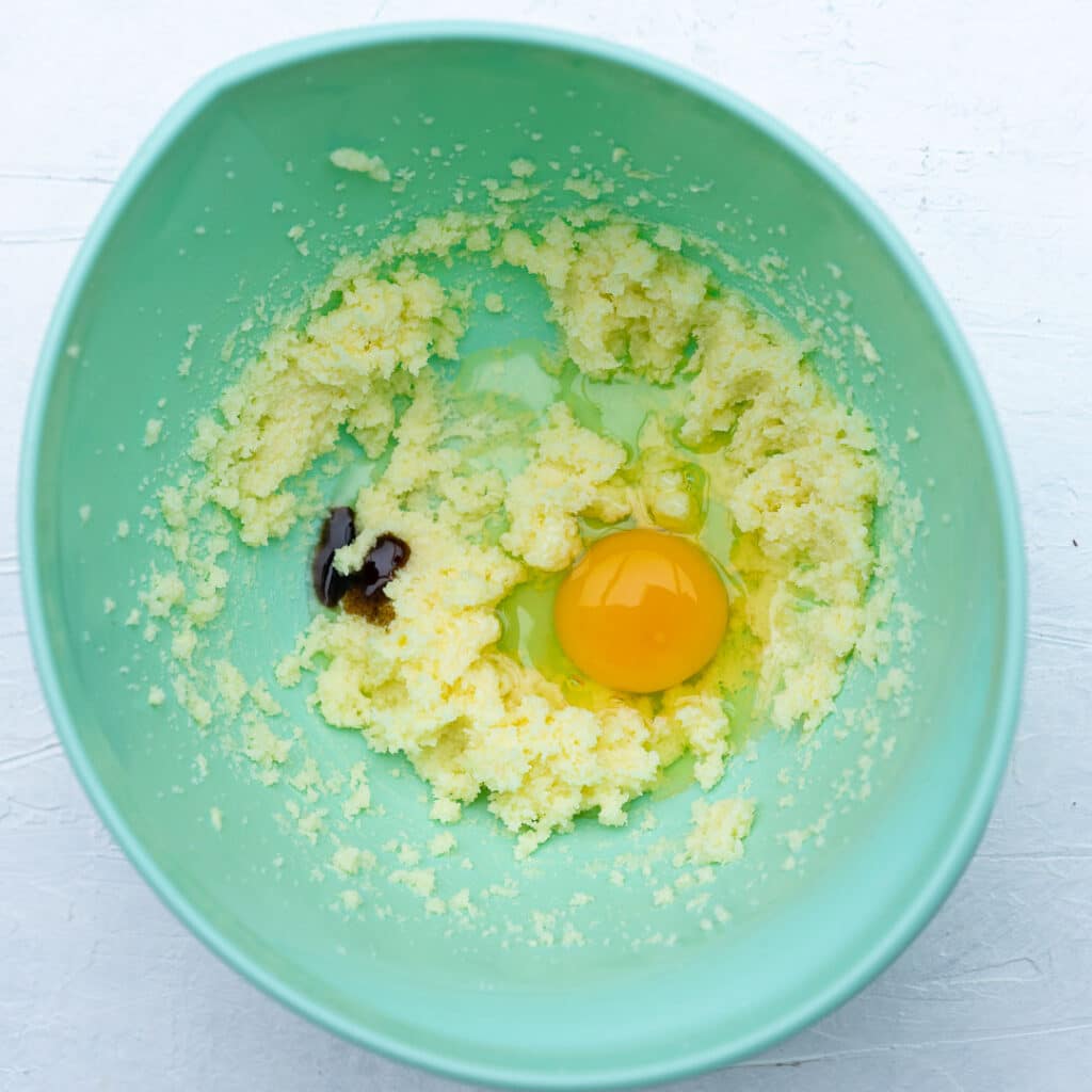 mixed butter and sugar with egg and vanilla in a turquoise bowl