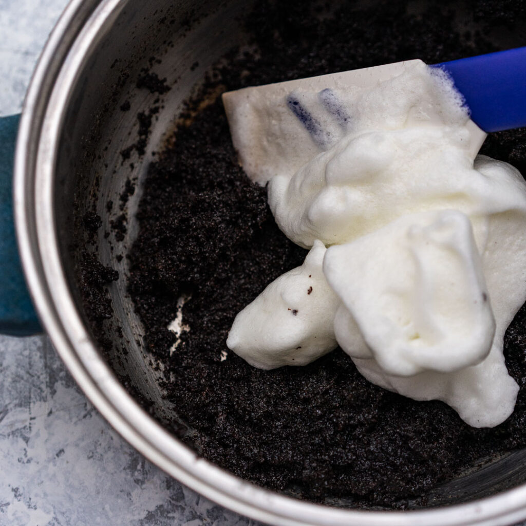 adding meringue to the poppy seed filling in a pot with a spatula
